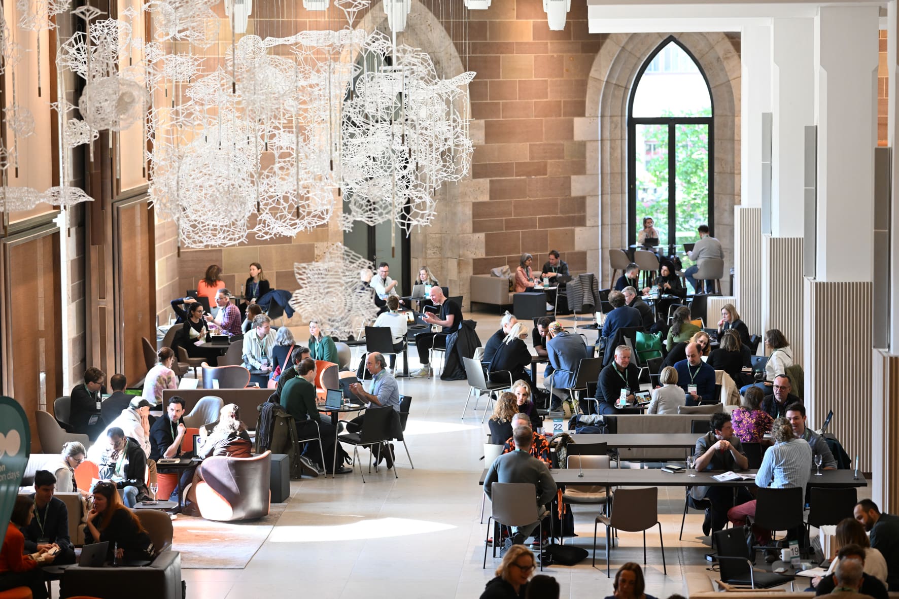 Blick ins Foyer des Landesmuseum Württemberg. Viele Menschen sitzen an Tischen zusammen und unterhalten sich.