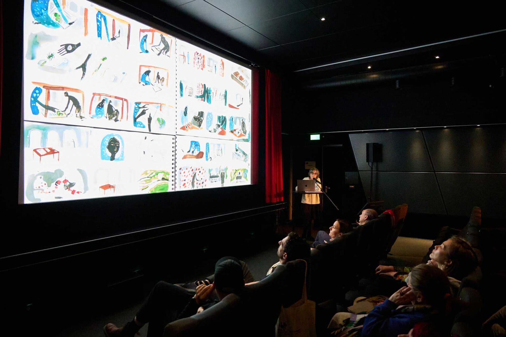 Blick auf die Kinoleinwand im Cinema Stuttgart. Eine Filmemacherin hält vor interessierten Zuhörern dazu einen Vortrag.