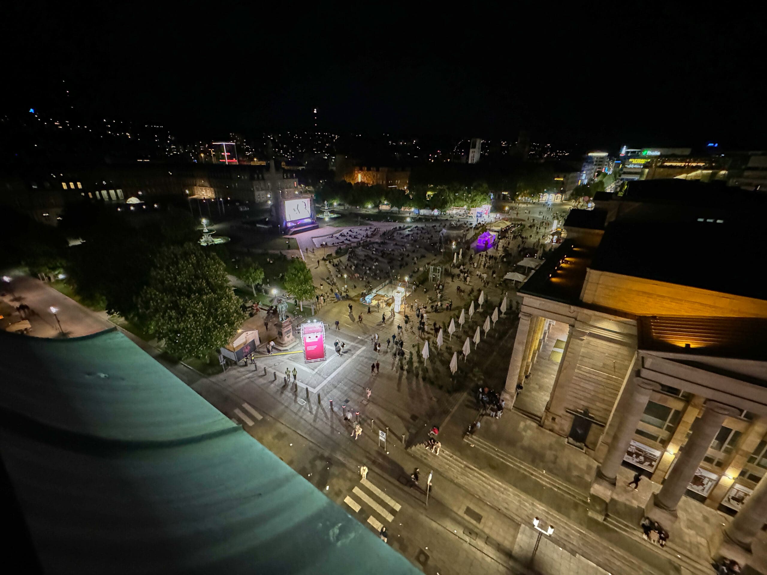 Blick von weit oben auf Schlossplatz mit Leinwand und Publikum nach Sonnenuntergang