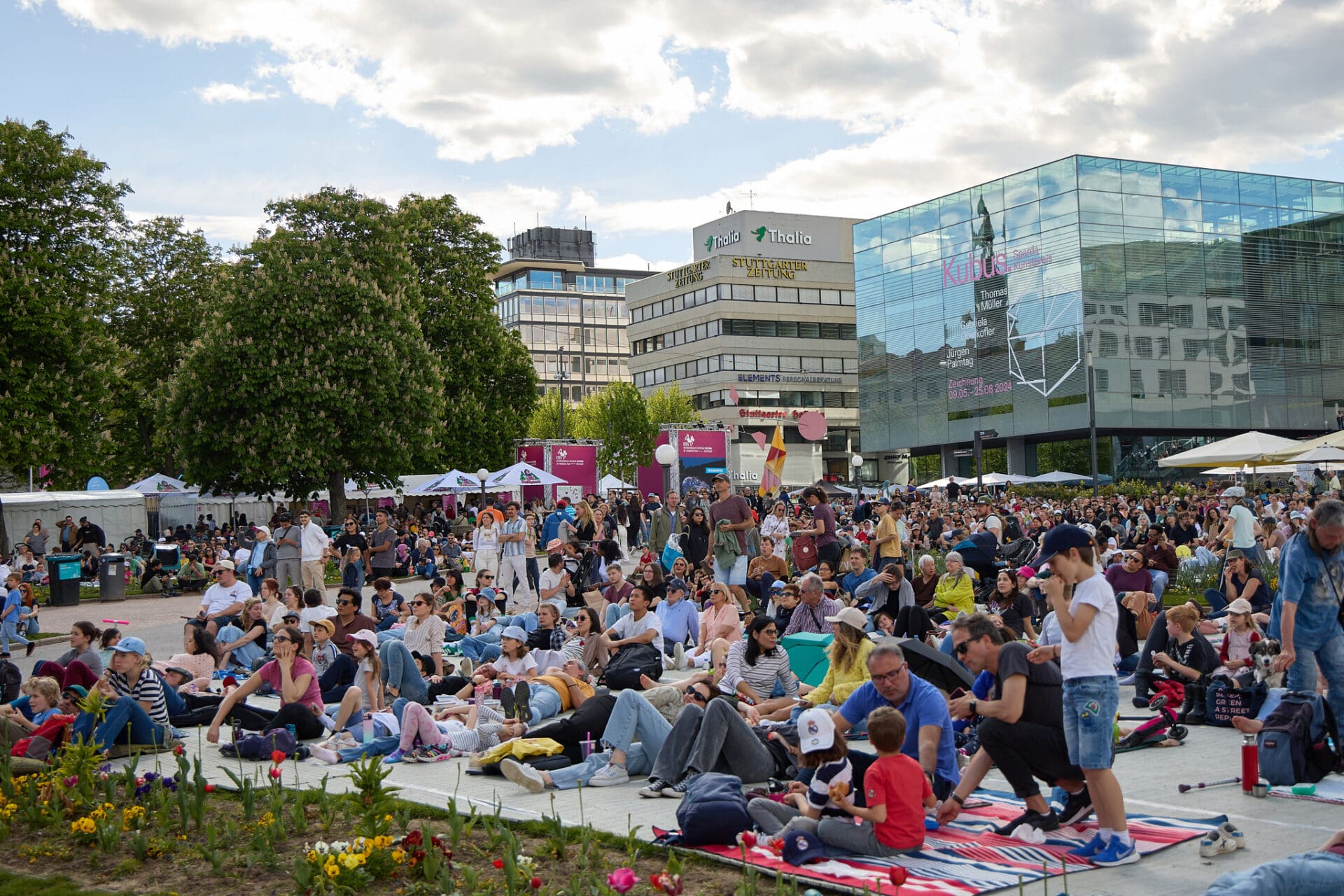 Publikum sitzt auf dem Stuttgarter Schlossplatz und schauen Filme