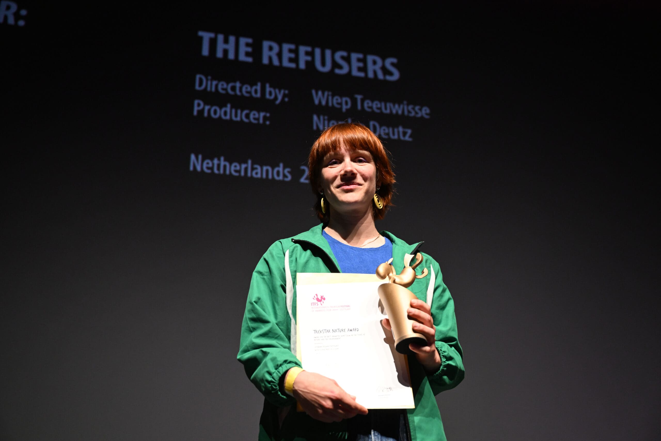 Preisträgerin mit Urkunde und Statue auf der Bühne